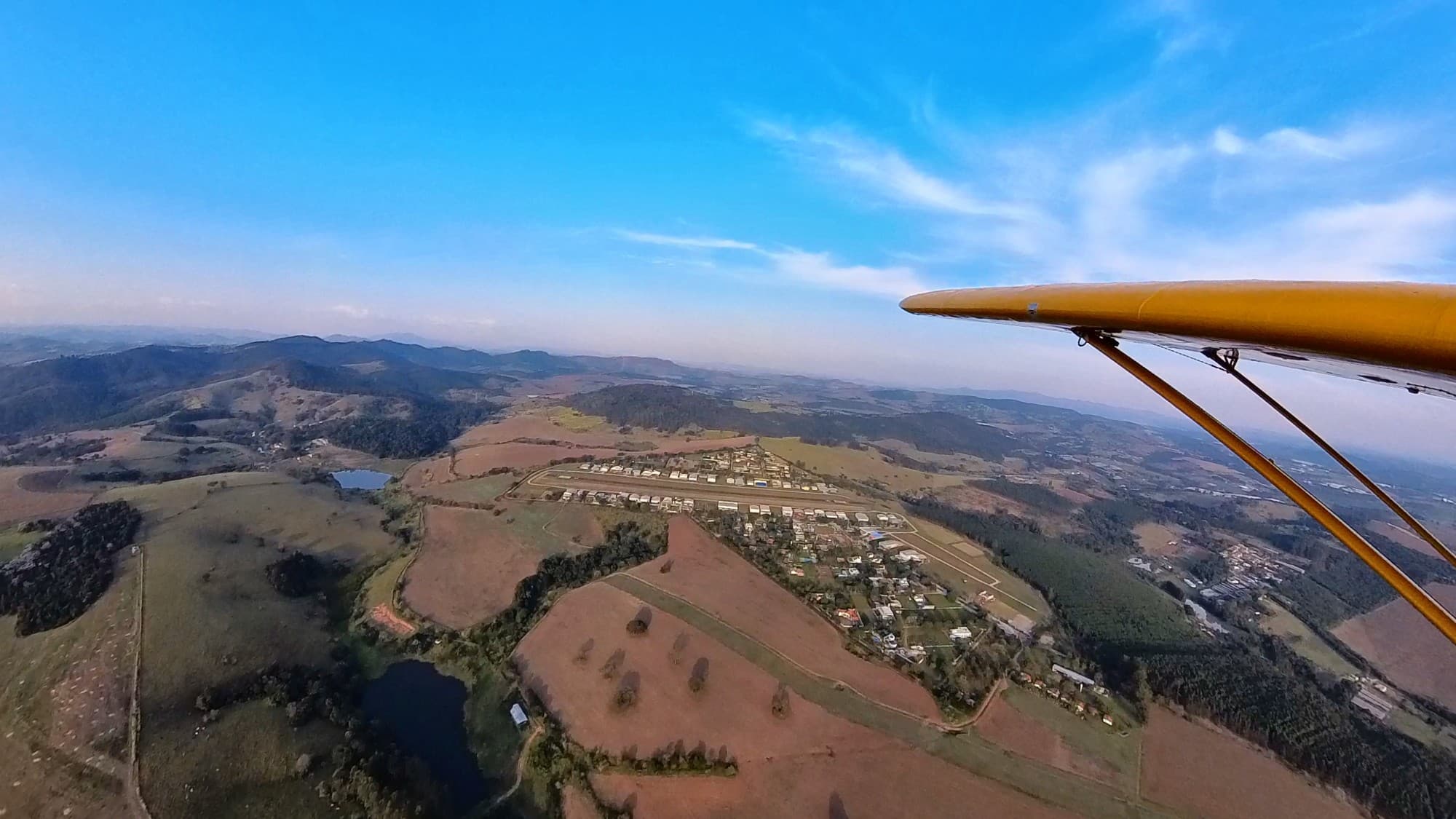 Vista da perna do vento da RWY 22: aeródromo à direita da asa, correndo paralelo à pista